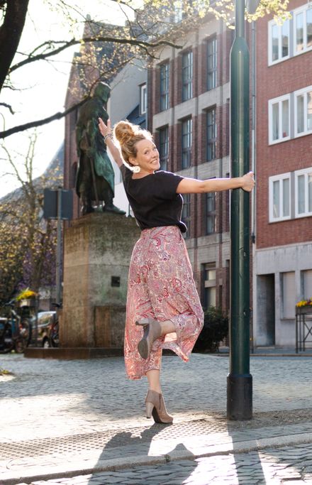 Mirka dreht sich froh in der Aachener Innenstadt an einer Laterne.