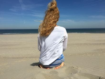 Mirka sitzt am Strand und blickt aufs Meer.